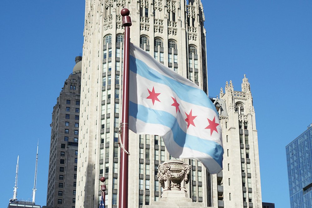 The Chicago flag waves in the wind on a flag pole in front of the Tribune Tower.