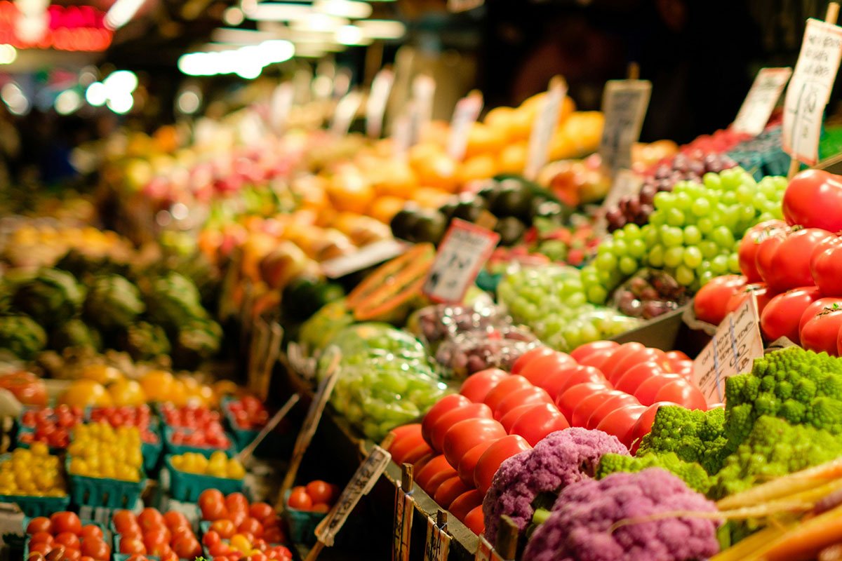 A photograph of a colorful produce aisle in a grocery store, with a shallow depth of field.