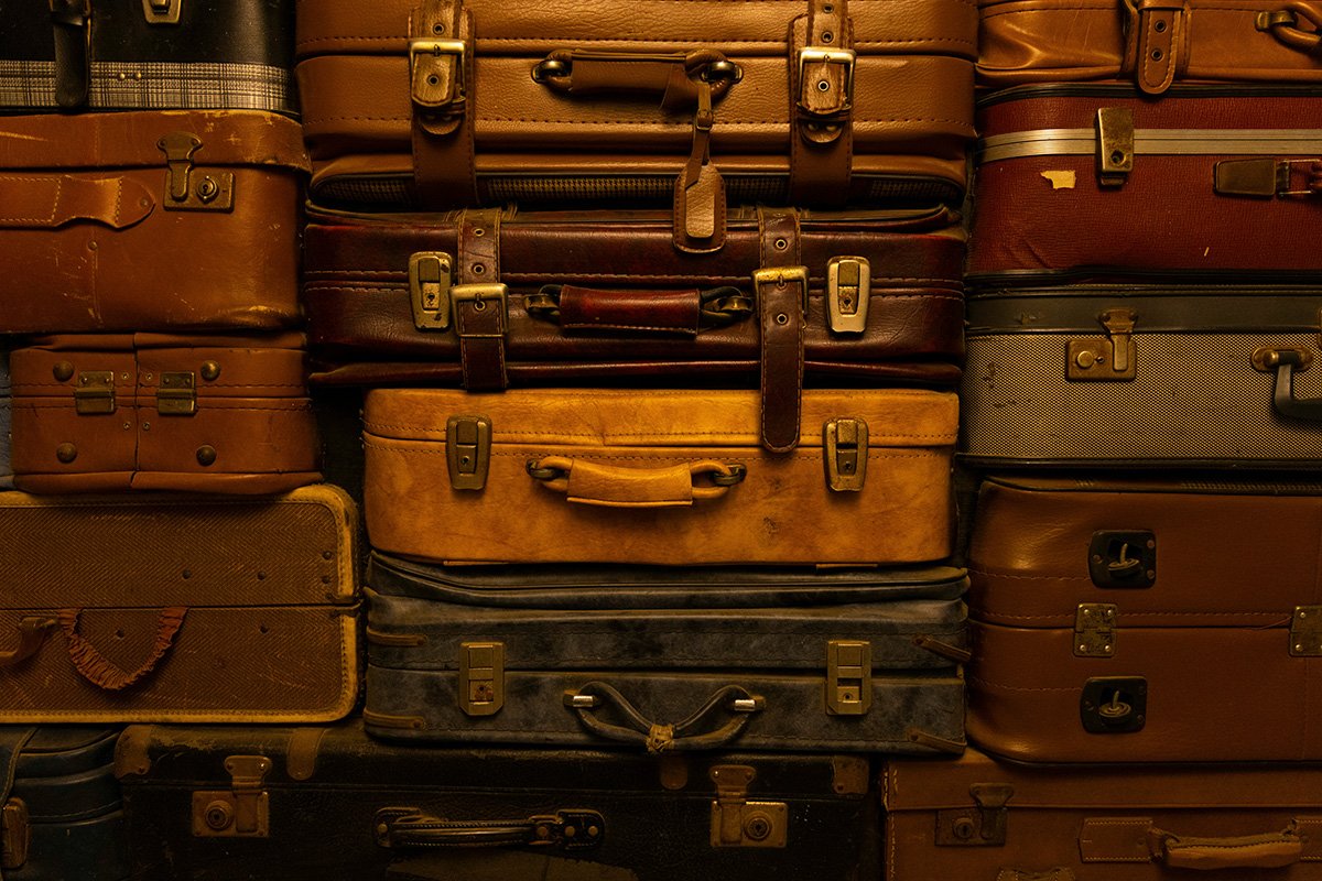 Tightly packed stacks of old, vintage-looking baggage. The handles and buckles face the camera