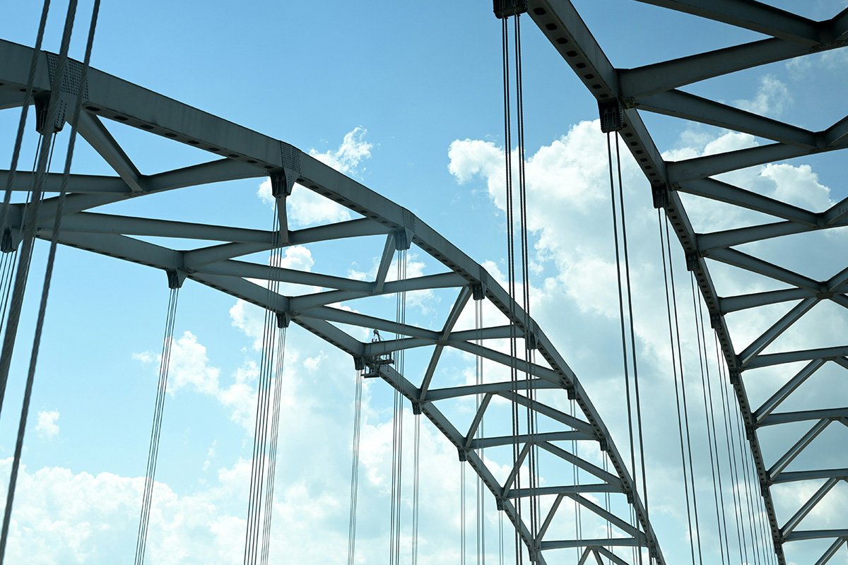 A close up of the arched top of a tension bridge, which manages environmental shock through flexibility and movement.